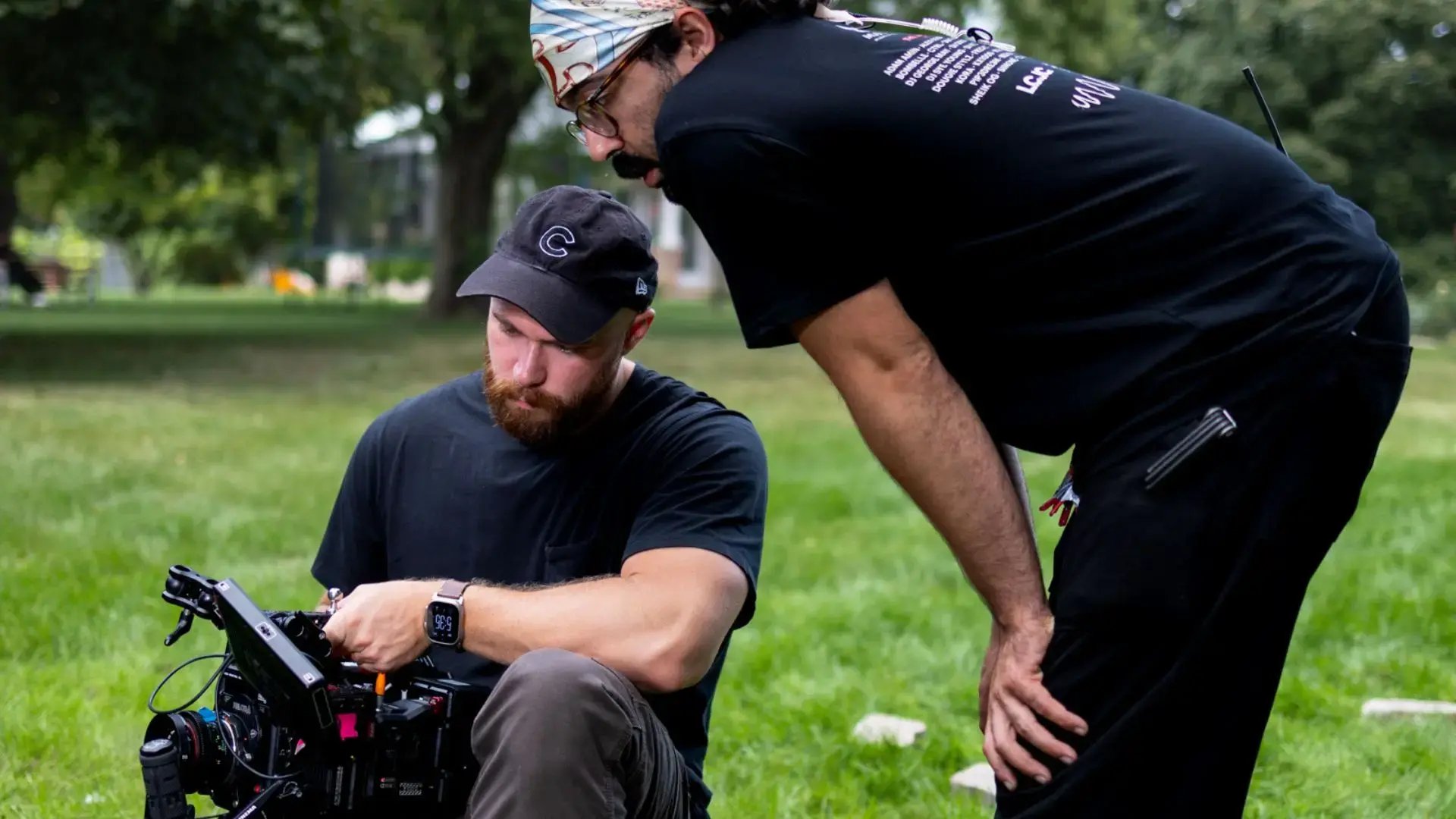 Two people talking while operating a cinema camera on a video production set