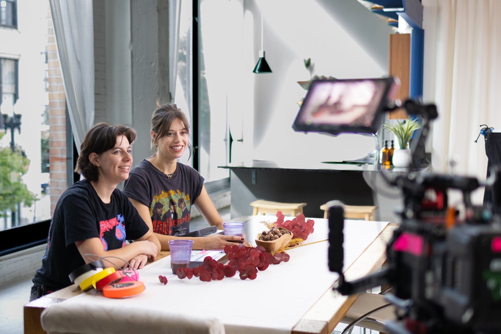 Two production crew members sit in front of a cinema camera to help with framing